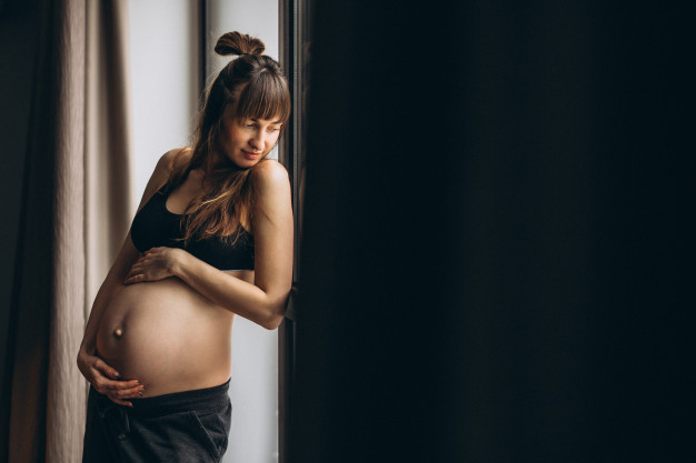 pregnant-woman-standing-by-window_1303-12879